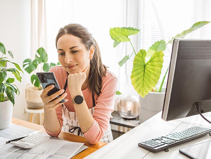 A young lady using her mobile phone at her office desk